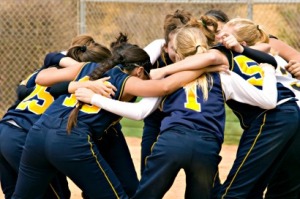 Softball team huddle before the start of a softball game in color.  All logos have been removed.